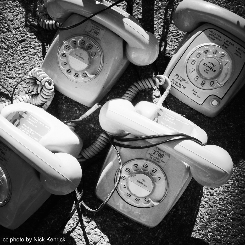 black and white photo of 4 rotary telephones from above