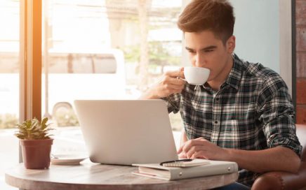 Man working on laptop drinking coffee
