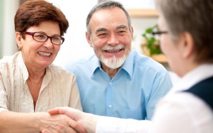 senior couple smiling while shaking hand with service advisor