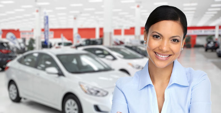 Woman with car dealership showroom in background