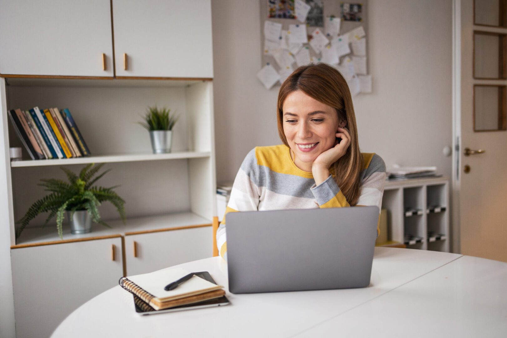 Woman smiling while using laptop at home.