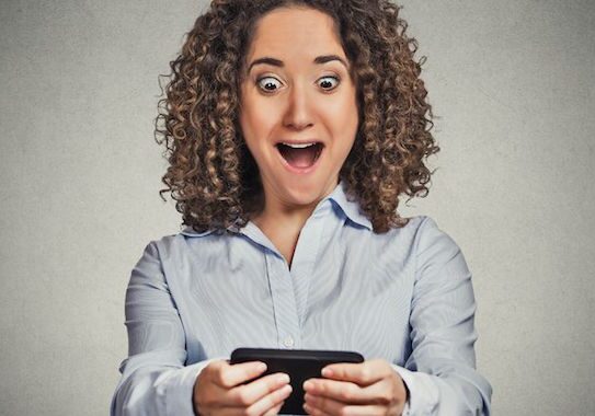 Woman excitedly looking at her phone.