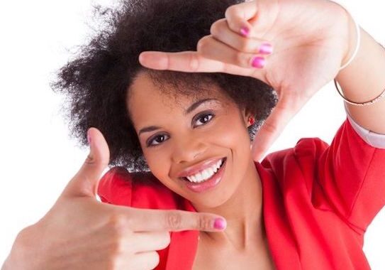 Woman smiling, framing face with hands.