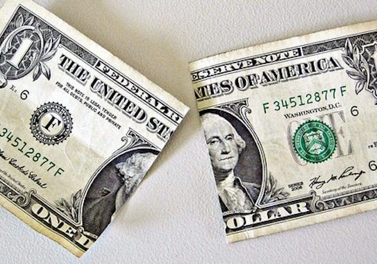 Torn one-dollar bill on a surface.