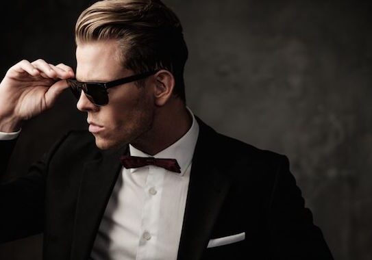 Man in suit wearing sunglasses confidently.